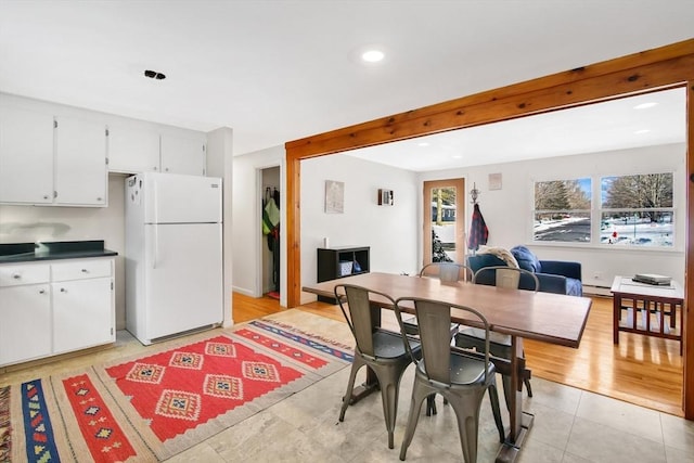 tiled dining space featuring beamed ceiling and a baseboard radiator