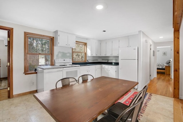 kitchen with white cabinetry, light tile patterned floors, and white appliances