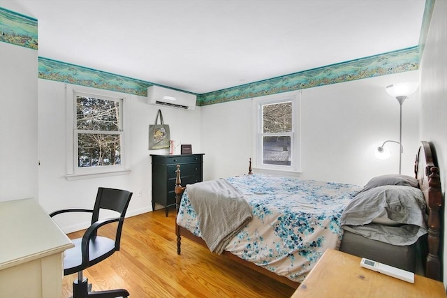 bedroom with hardwood / wood-style floors and a wall mounted AC