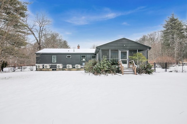 snow covered house featuring a sunroom