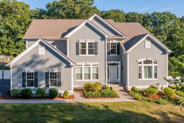 view of front of home featuring a front lawn and a shingled roof