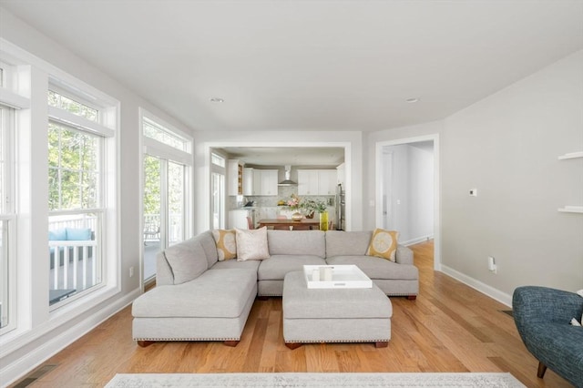 living area featuring visible vents, light wood-type flooring, and baseboards