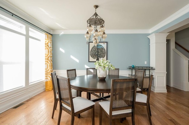 dining room featuring visible vents, an inviting chandelier, decorative columns, ornamental molding, and light wood-type flooring