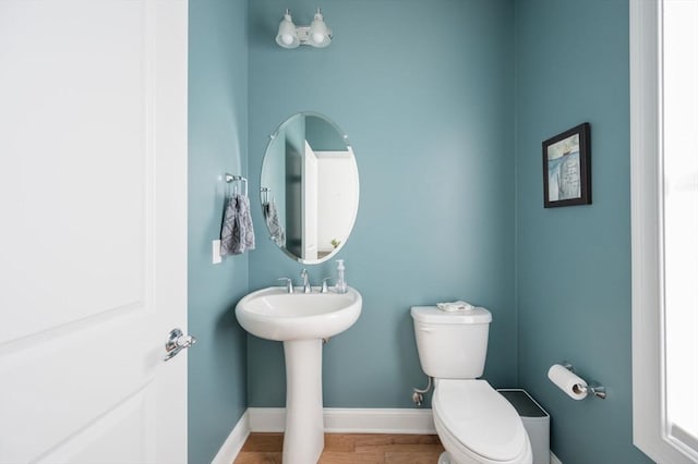 half bath featuring toilet, baseboards, and wood finished floors