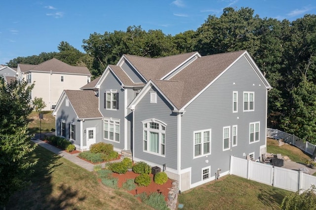 view of front of property with a front yard, fence, and a shingled roof