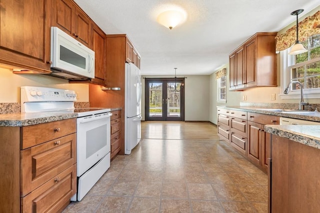 kitchen featuring white appliances, french doors, plenty of natural light, and a sink