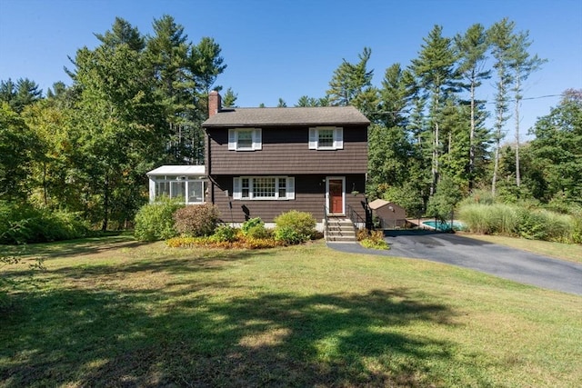colonial house featuring a front yard and a chimney