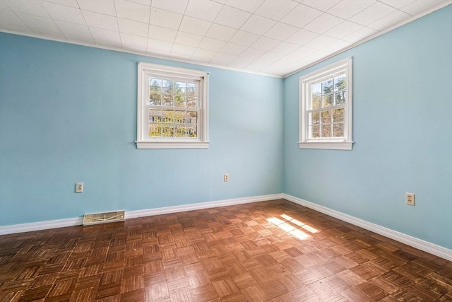 spare room featuring baseboards, a wealth of natural light, and visible vents