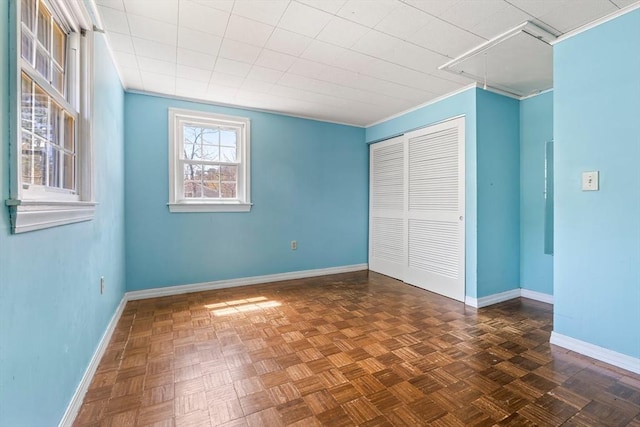 unfurnished bedroom featuring a closet, attic access, baseboards, and crown molding