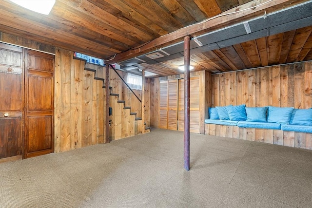 finished below grade area featuring stairway, carpet floors, wood ceiling, and wood walls