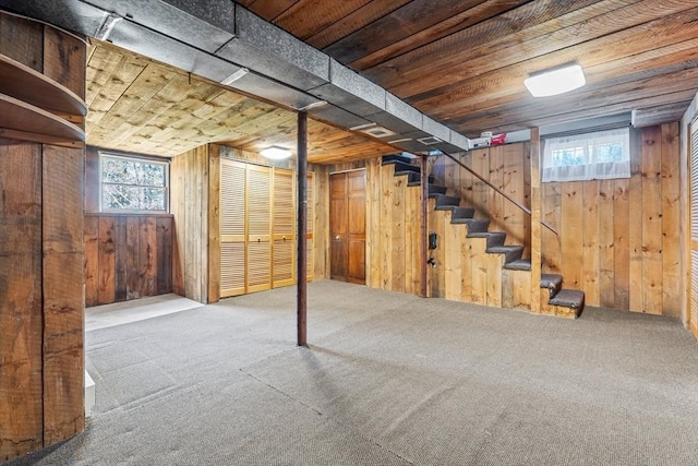 below grade area featuring wooden walls, carpet flooring, and stairs