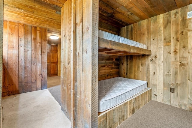unfurnished bedroom with wooden ceiling, carpet, and wood walls