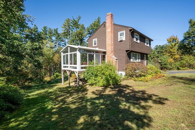 view of home's exterior with a yard, a chimney, and a sunroom