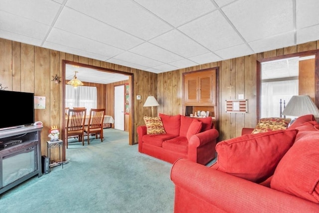 carpeted living room with a paneled ceiling and wood walls