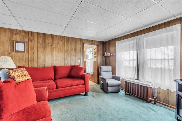 carpeted living room featuring radiator heating unit and wooden walls