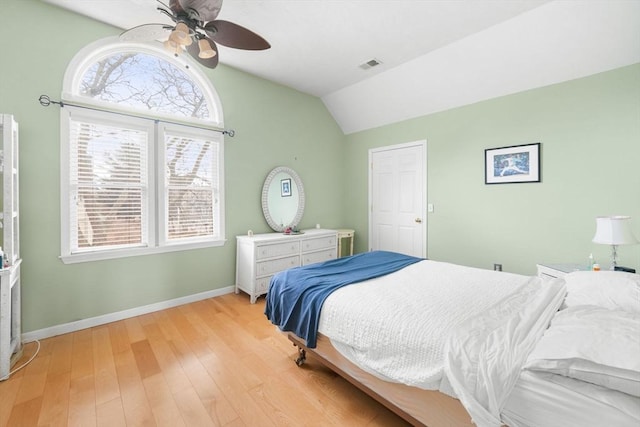 bedroom with lofted ceiling, multiple windows, baseboards, and light wood-style floors