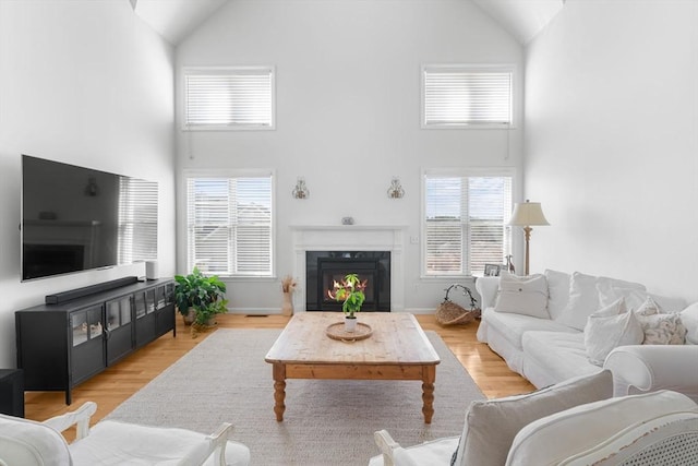 living room featuring light wood-style flooring, high vaulted ceiling, and a high end fireplace