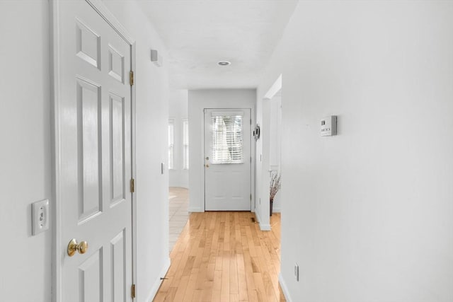 hall with light wood-style floors and baseboards