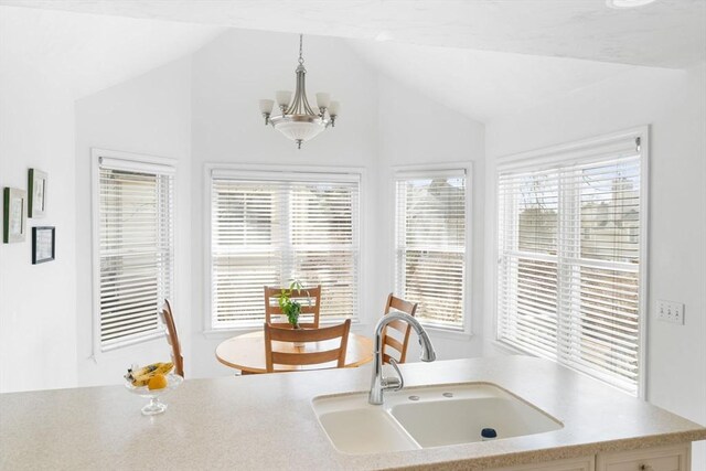 kitchen featuring lofted ceiling, a chandelier, a sink, light countertops, and pendant lighting