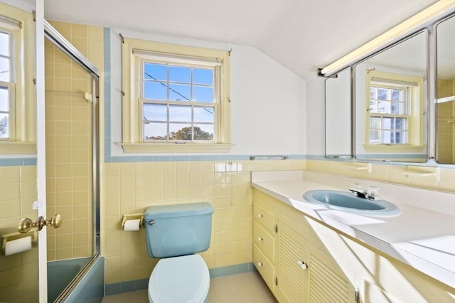 bathroom featuring tile walls, bath / shower combo with glass door, toilet, vaulted ceiling, and vanity