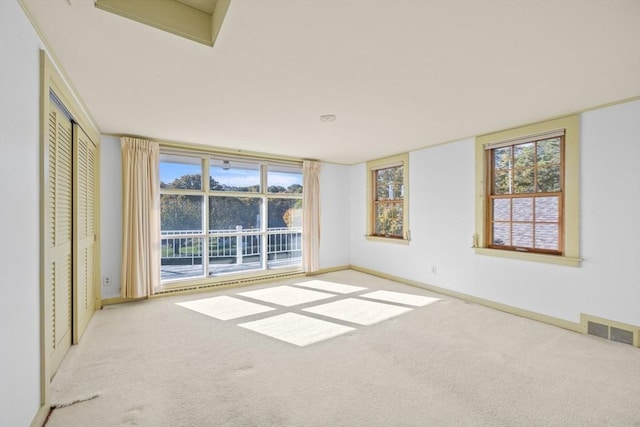 spare room with a healthy amount of sunlight, carpet, visible vents, and baseboards