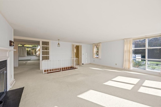 unfurnished living room with a fireplace with flush hearth, a baseboard heating unit, carpet floors, and baseboards