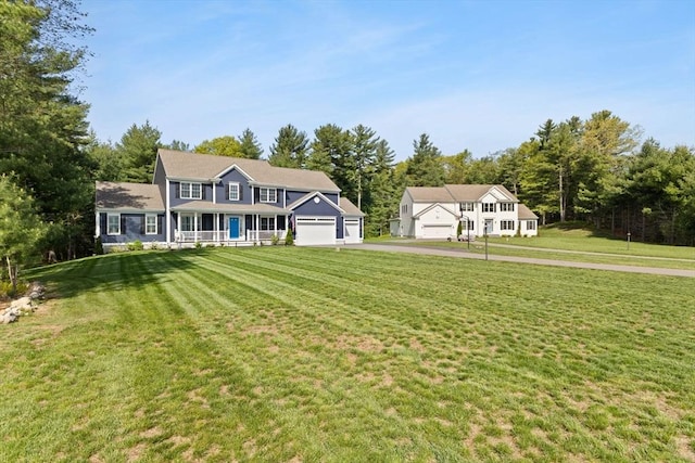 colonial house featuring asphalt driveway, a front yard, covered porch, and an attached garage