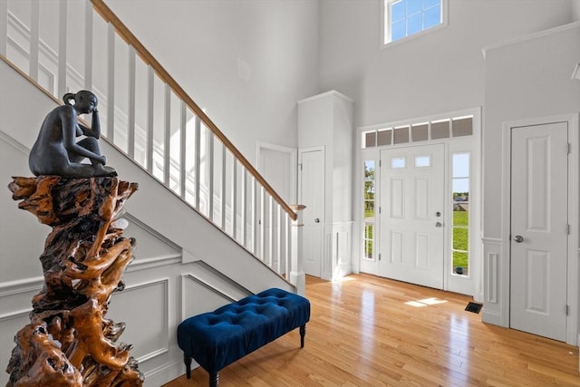entryway with a towering ceiling, stairway, and light wood-style flooring