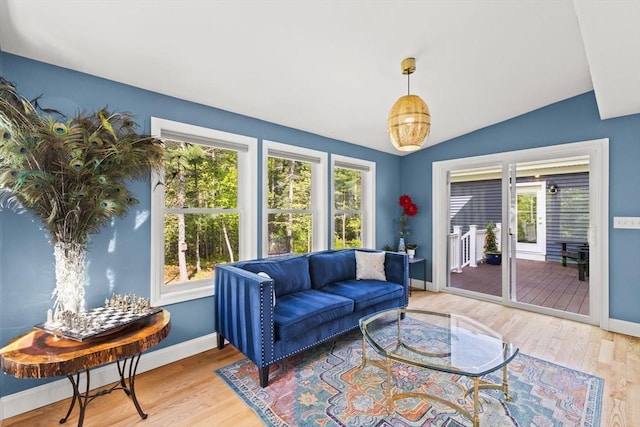living room featuring vaulted ceiling, baseboards, and wood finished floors