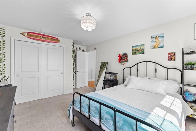 bedroom featuring light colored carpet, a closet, and a chandelier