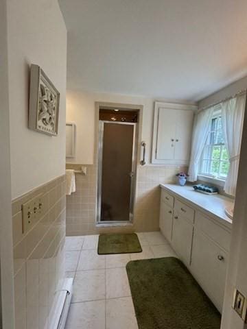 18 Lily Pond Dr, Yarmouth, MA 02664 - bathroom featuring tile walls, tile patterned flooring, a stall shower, a baseboard radiator, and a wainscoted wall