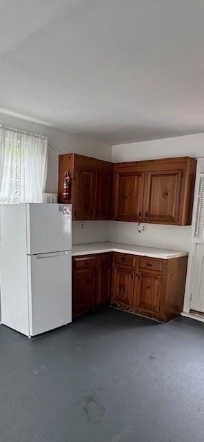 18 Lily Pond Dr, Yarmouth, MA 02664 - kitchen with freestanding refrigerator, light countertops, concrete floors, and brown cabinets