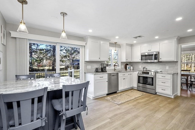 kitchen with light wood-style flooring, visible vents, appliances with stainless steel finishes, and tasteful backsplash