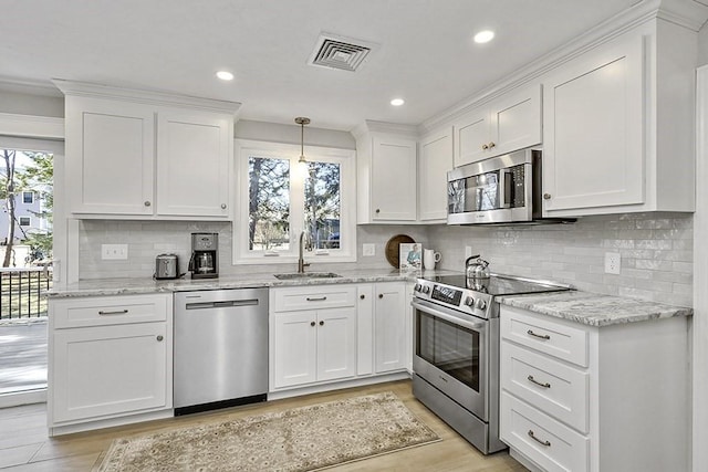 kitchen featuring light wood finished floors, visible vents, appliances with stainless steel finishes, white cabinets, and a sink