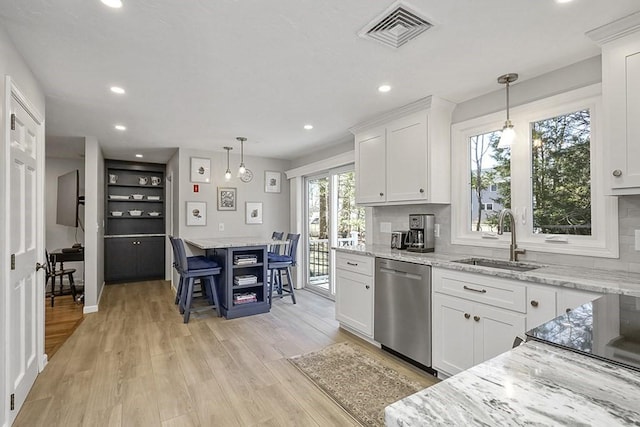 kitchen featuring a sink, visible vents, white cabinets, light wood-style floors, and dishwasher