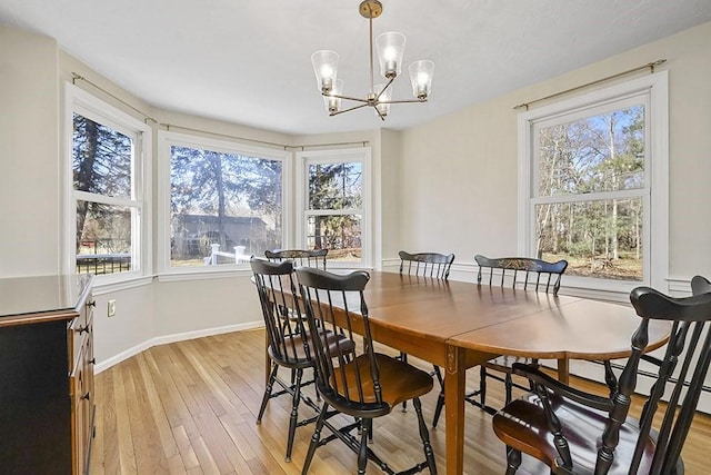 dining area featuring light wood-style floors, a chandelier, and baseboards