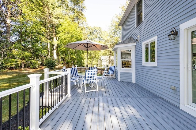 wooden terrace with outdoor dining area and a lawn