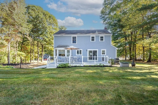 rear view of house with a lawn, a chimney, and a wooden deck