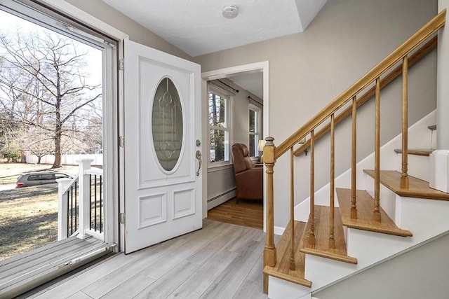 entrance foyer with stairway, a baseboard radiator, and wood finished floors