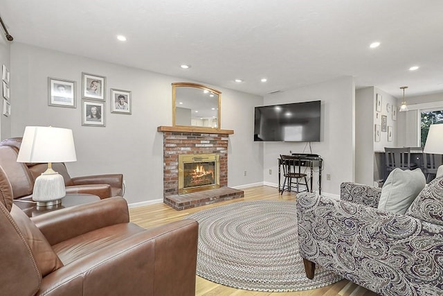 living room with recessed lighting, a brick fireplace, and wood finished floors