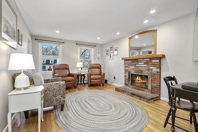 living area featuring a fireplace, baseboards, baseboard heating, and wood finished floors