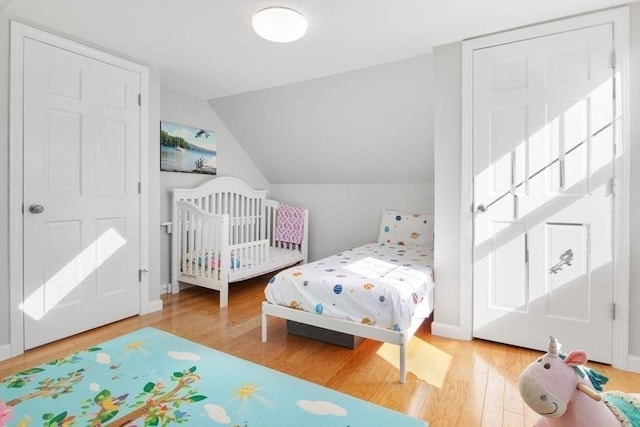 bedroom featuring lofted ceiling, baseboards, and wood finished floors