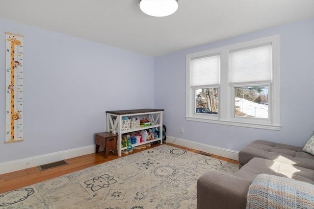 sitting room with baseboards, visible vents, and wood finished floors