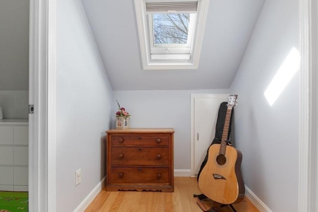 interior space featuring lofted ceiling, light wood-style floors, and baseboards