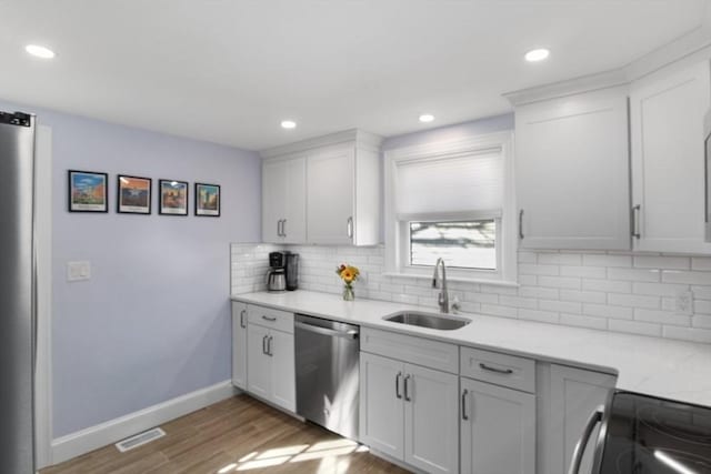 kitchen featuring wood finished floors, a sink, baseboards, backsplash, and dishwasher