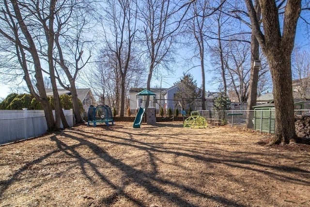 view of yard with a trampoline, playground community, and fence