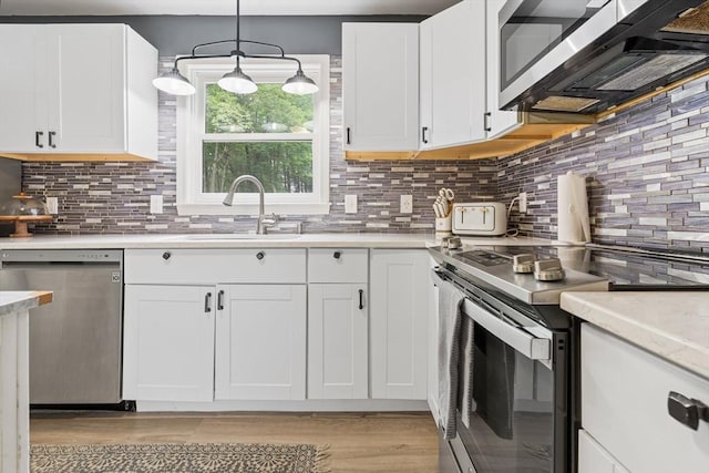 224 Church, Pembroke, NH 03275 - kitchen featuring appliances with stainless steel finishes, light countertops, light wood-style flooring, white cabinets, and tasteful backsplash