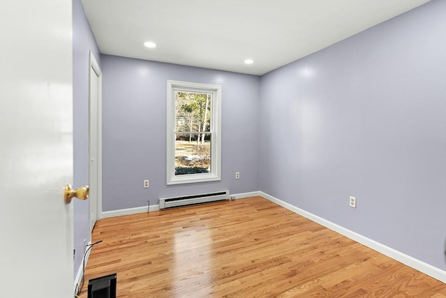 unfurnished room featuring baseboard heating and light hardwood / wood-style flooring