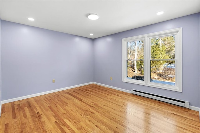 unfurnished room featuring light wood-type flooring and a baseboard heating unit