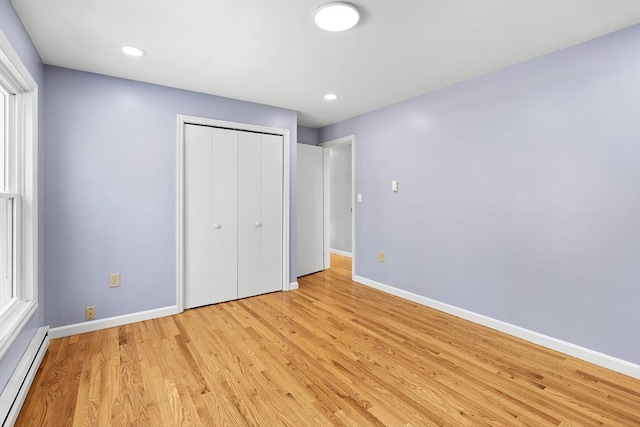 unfurnished bedroom featuring a closet, light hardwood / wood-style floors, and a baseboard radiator